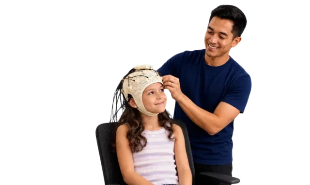 Technician adjusting EEG cap on a smiling girl seated in a chair.